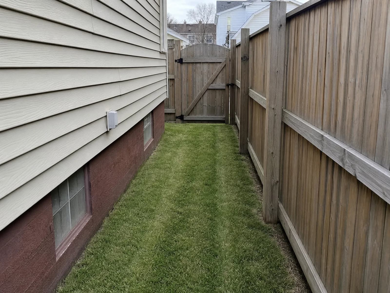 Narrow fenced side yard after push mowing and trimming.